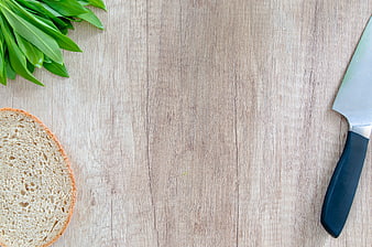 Fresh wild garlic, bread slice, and knife on wooden background
