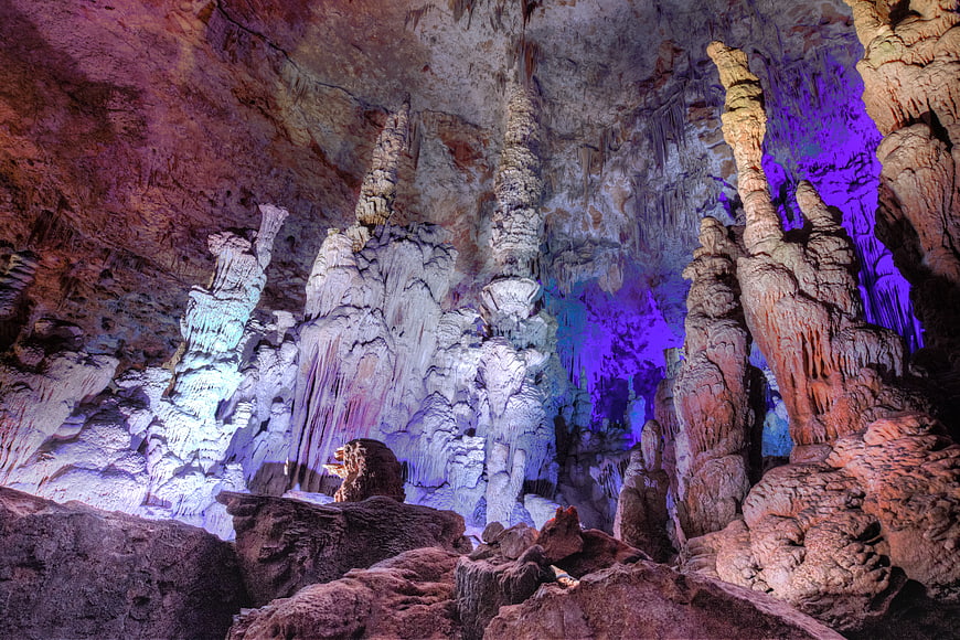 Colorful stalactites and stalagmites in a large cave interior