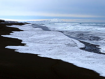 Frozen Black Sand Beach with Snow-Capped Mountains