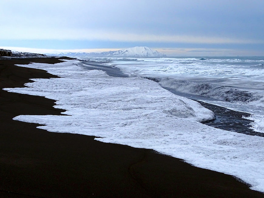 Frozen Black Sand Beach with Snow-Capped Mountains