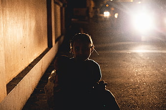 Silhouette of woman holding baby on dark street at night