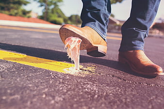Cowboy boot stepping on chewed gum on asphalt road