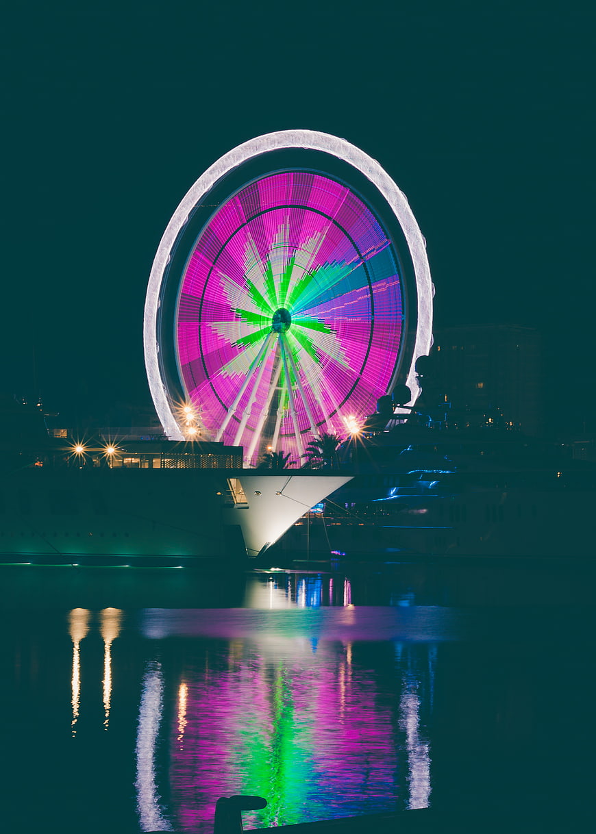 Illuminated Ferris Wheel at Night with Vibrant Reflections