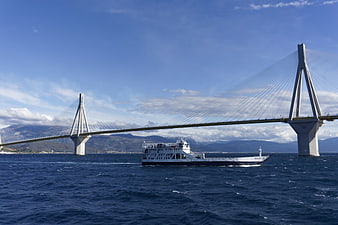 Ferry boat passing under large cable-stayed bridge at sea