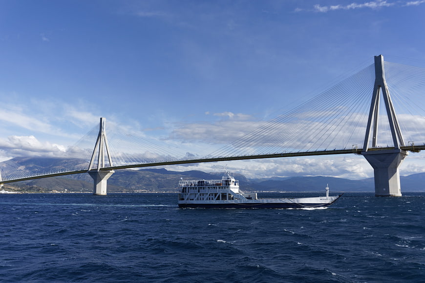 Ferry boat passing under large cable-stayed bridge at sea