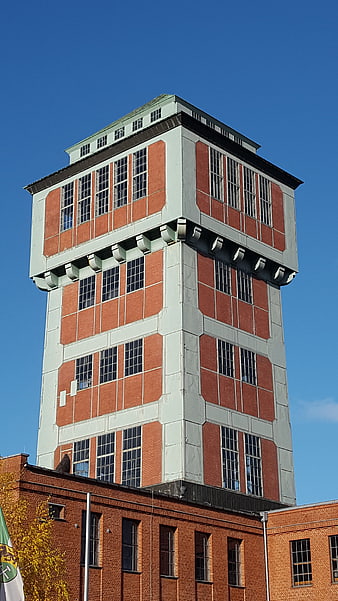 Historic red brick industrial tower against blue sky