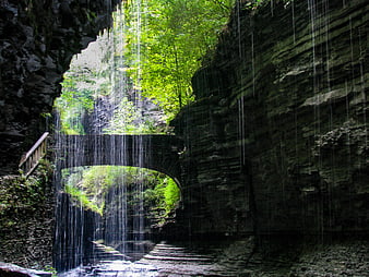 Waterfall cascading through stone arch bridge in forest
