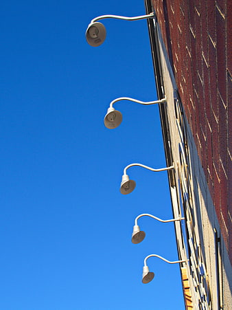 White street lamps on brick wall against blue sky