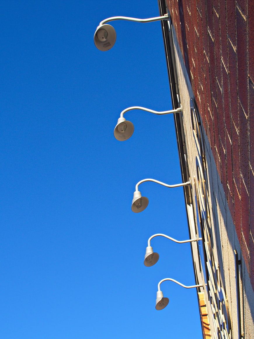 White street lamps on brick wall against blue sky
