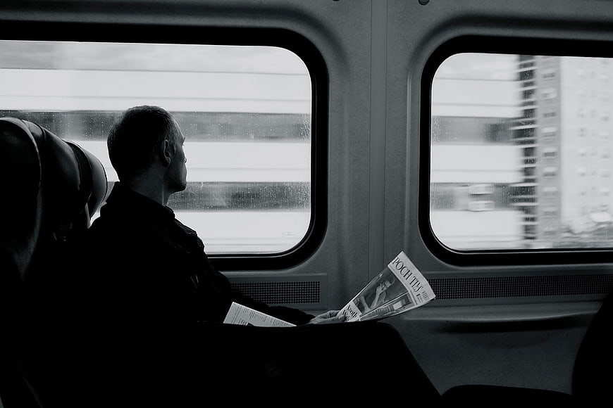Silhouette of Man Reading Magazine on Moving Train