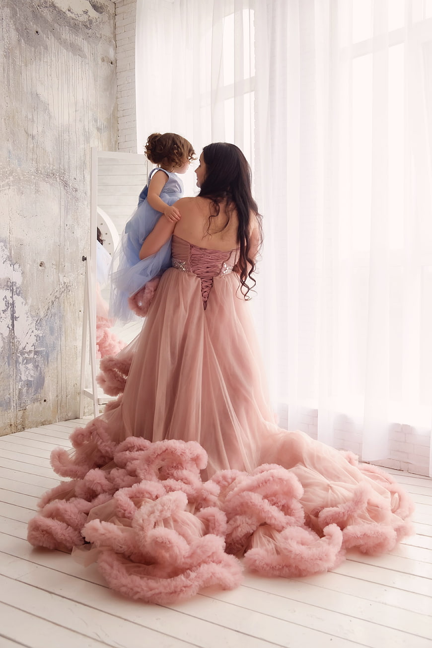 Mother and daughter in pink and blue dresses looking in mirror