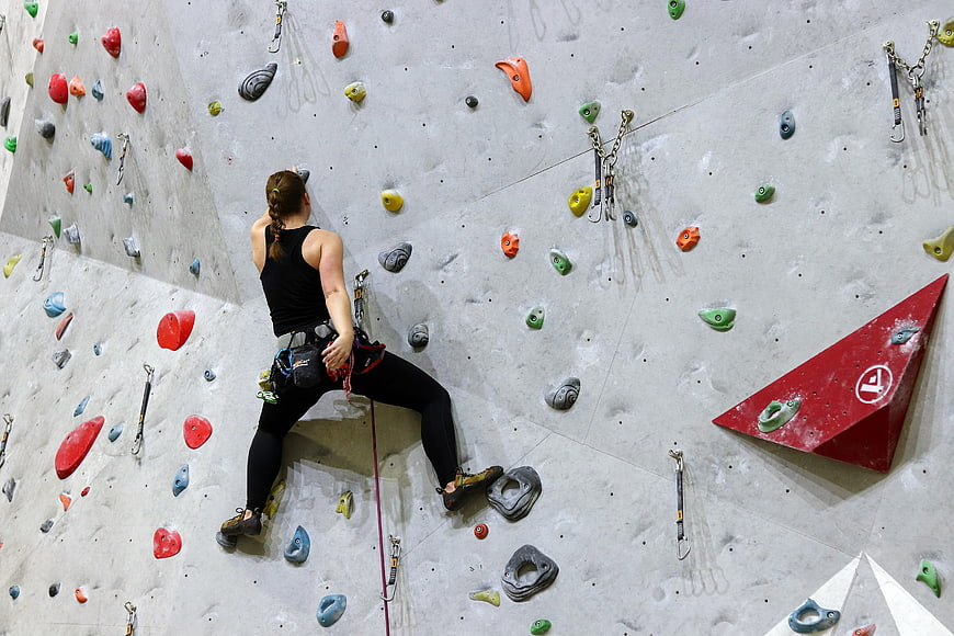 Woman rock climbing on indoor wall with colorful holds