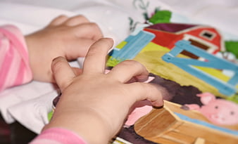 Baby hands touching colorful farm book page