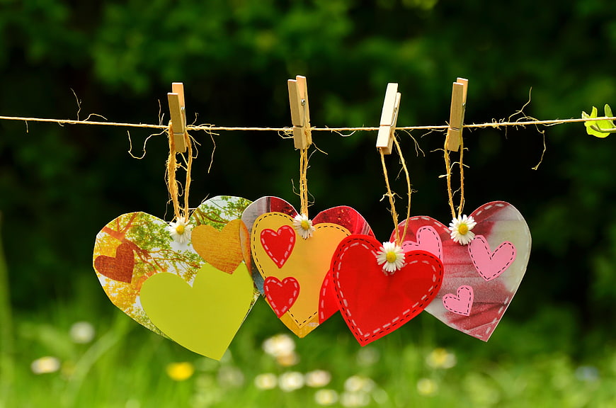Colorful paper hearts hanging on a clothesline outdoors