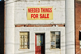 Weathered storefront with 'Needed Things For Sale' sign