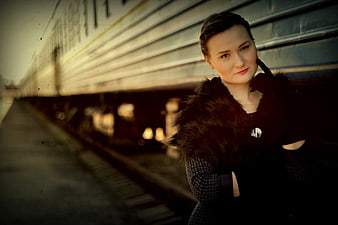 Woman in Fur Coat Standing by Train at Sunset
