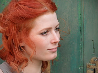 Close-up portrait of woman with red hair against green door