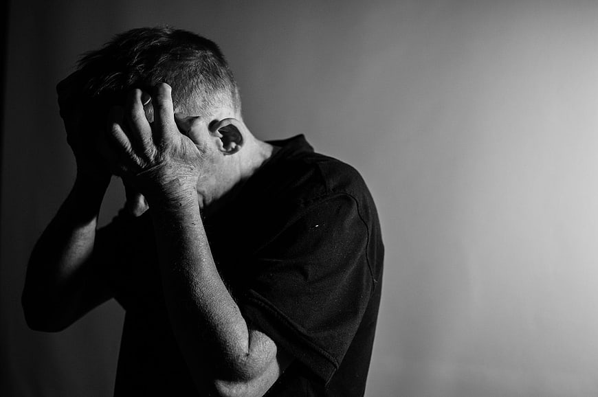 Black and white portrait of distressed man holding head