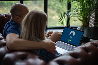 Couple using laptop with VPN on leather sofa