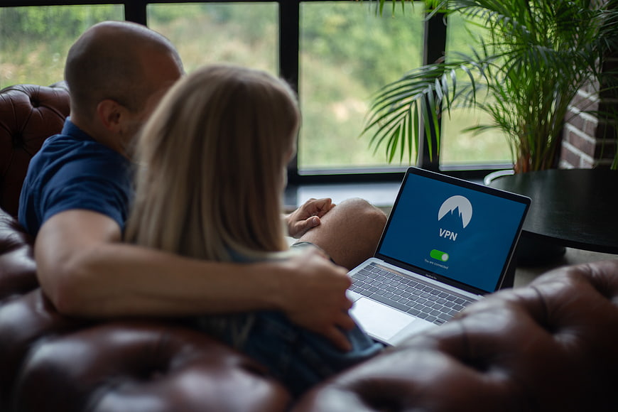 Couple using laptop with VPN on leather sofa