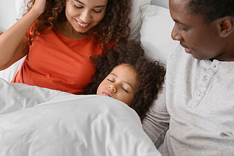 Happy African American Family Sleeping in Bed Together