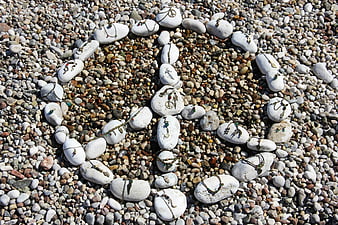 Peace sign made of white stones and jewelry on pebble beach