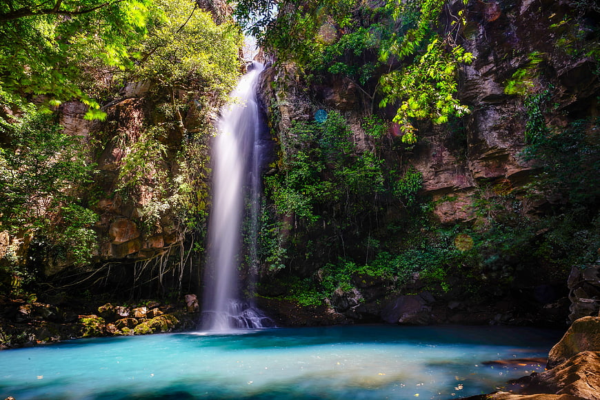 Tropical waterfall cascading into turquoise pool in lush jungle