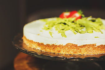 Close-up of creamy cheesecake with strawberry and pistachio garnish