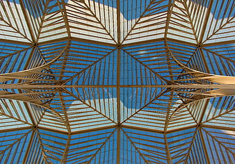 Symmetrical steel and glass ceiling architecture against blue sky
