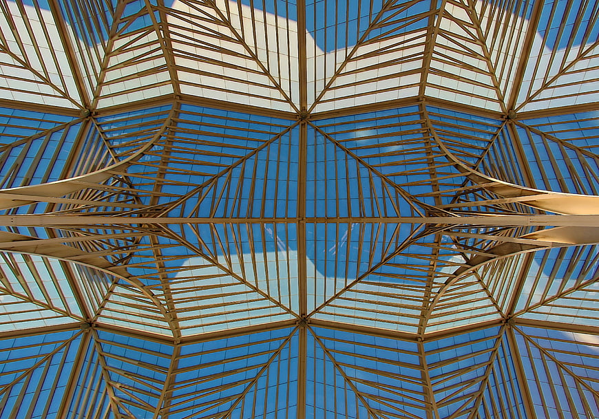 Symmetrical steel and glass ceiling architecture against blue sky