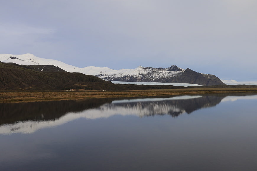 Serene Icelandic Landscape with Snow-Capped Mountains and Glacier Reflection