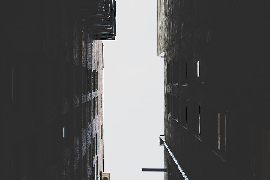 Low angle view of urban buildings against white sky