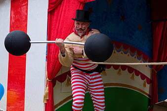 Circus Strongman Performing Illusion Act With Fake Dumbbell