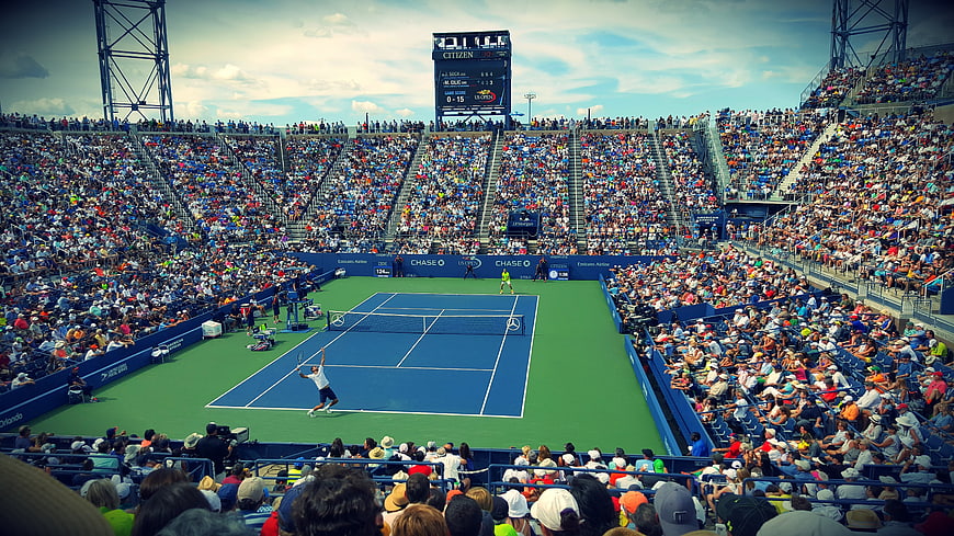 Wide shot of professional tennis match in packed stadium