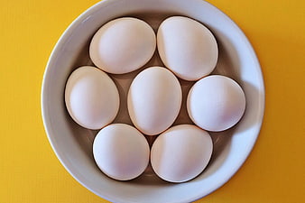 Top View of White Eggs in White Bowl on Yellow Background