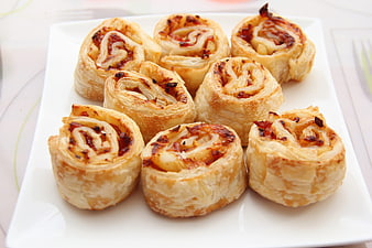 Golden baked savory pastry rolls on white plate