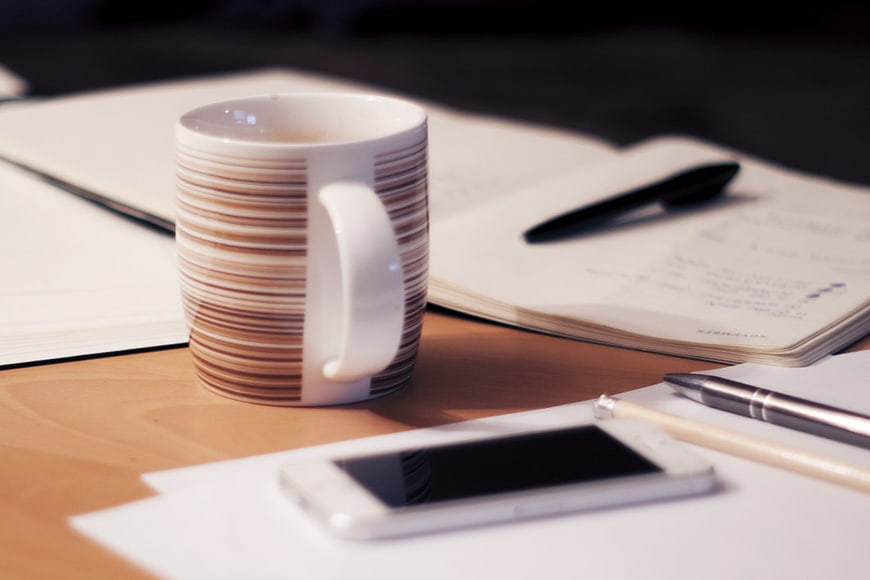 Coffee Mug on Wooden Desk with Notebook and Smartphone