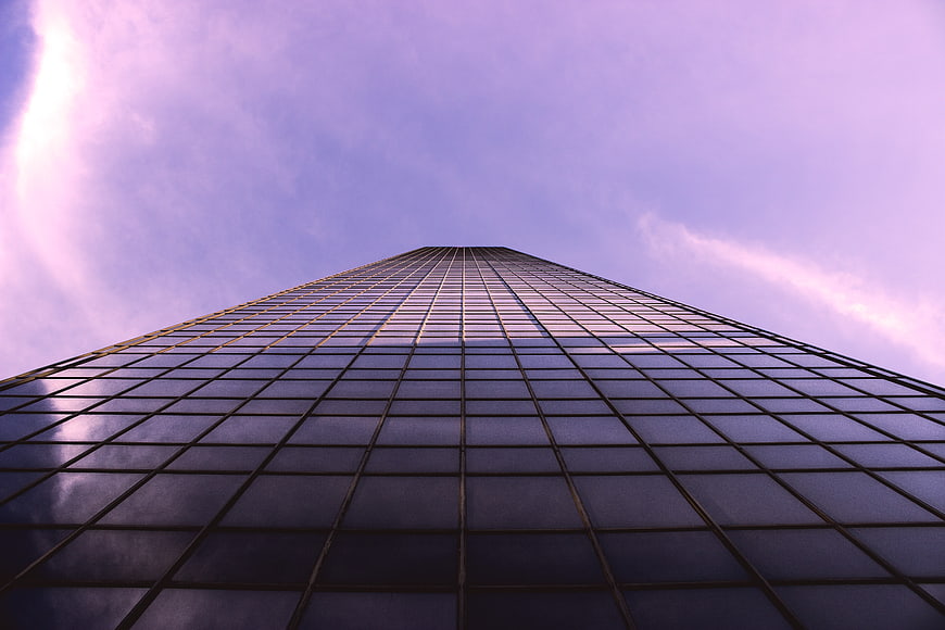 Low angle view of modern glass skyscraper against purple sky