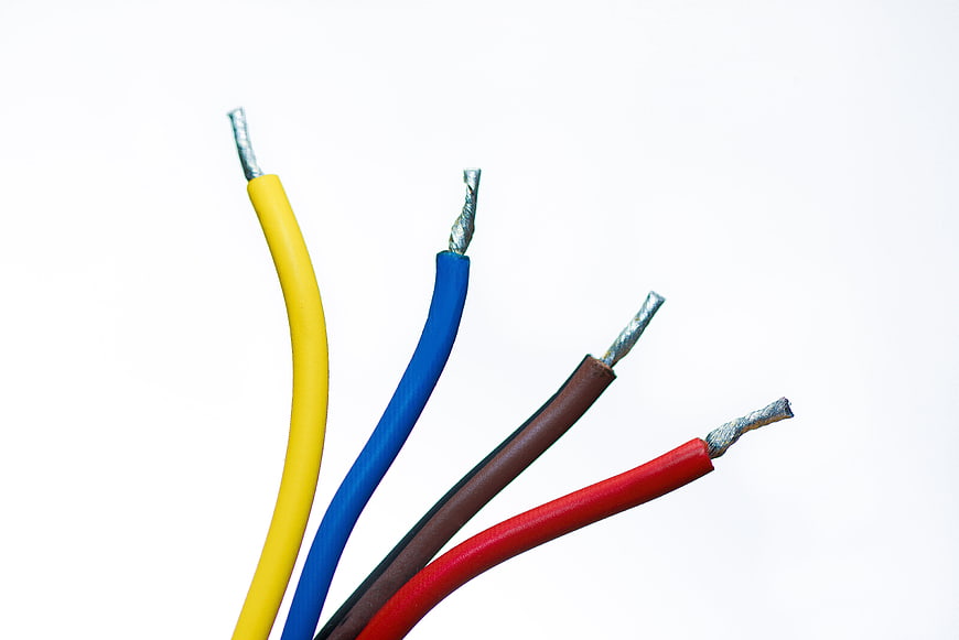 Colorful electrical wires with exposed copper tips on white background