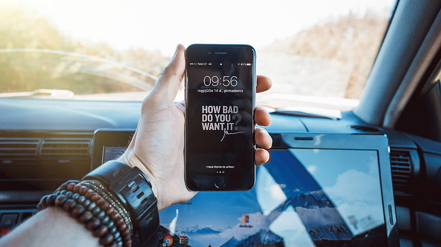 Hand holding smartphone with motivational quote in car