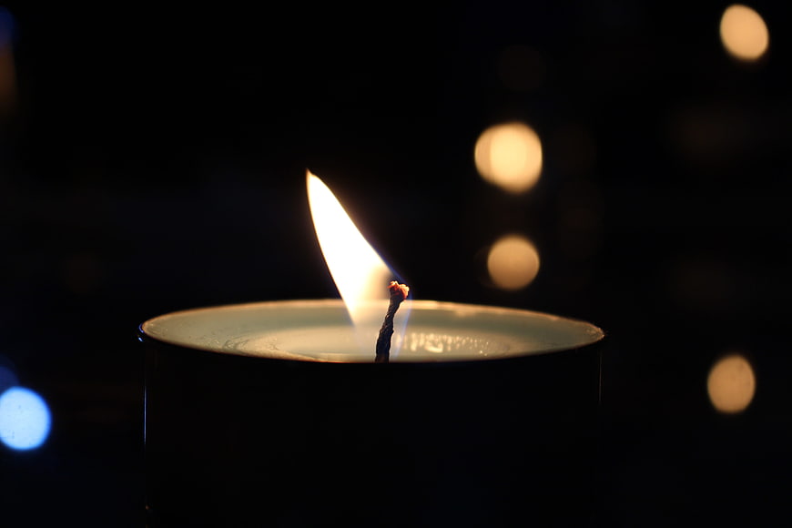 Close-up of a lit candle flame in the dark with bokeh