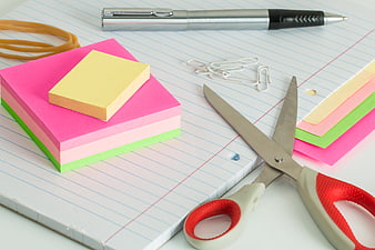 Colorful sticky notes, scissors, and pen on lined notebook