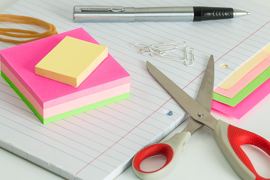 Colorful sticky notes, scissors, and pen on lined notebook