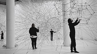 Visitors interacting with large-scale wire network art installation in gallery