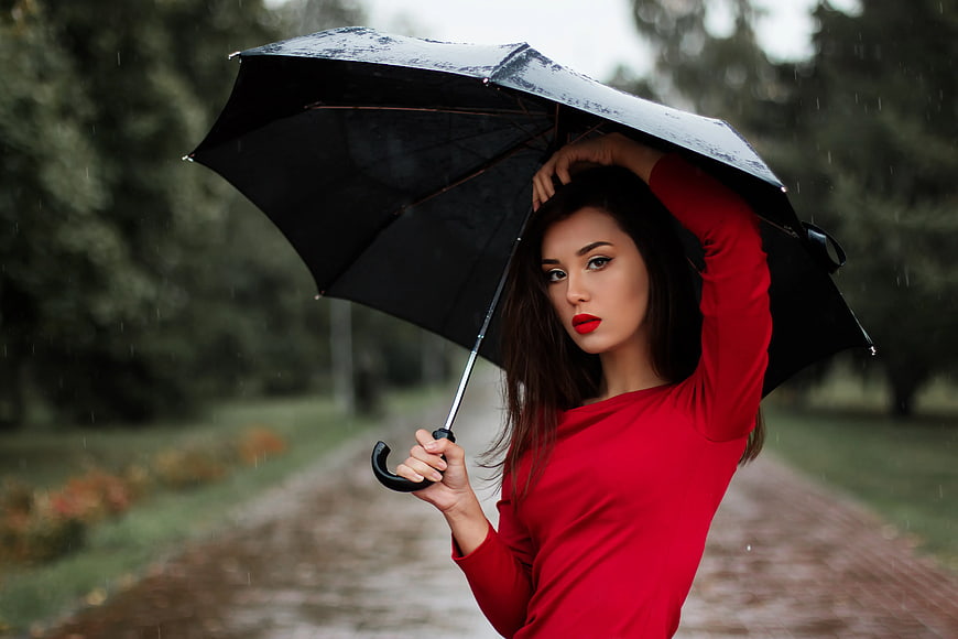 Woman in Red Dress Holding Black Umbrella in Rain