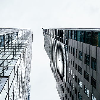 Low angle view of modern glass skyscrapers against white sky