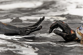 Two hands covered in black paint reaching toward each other