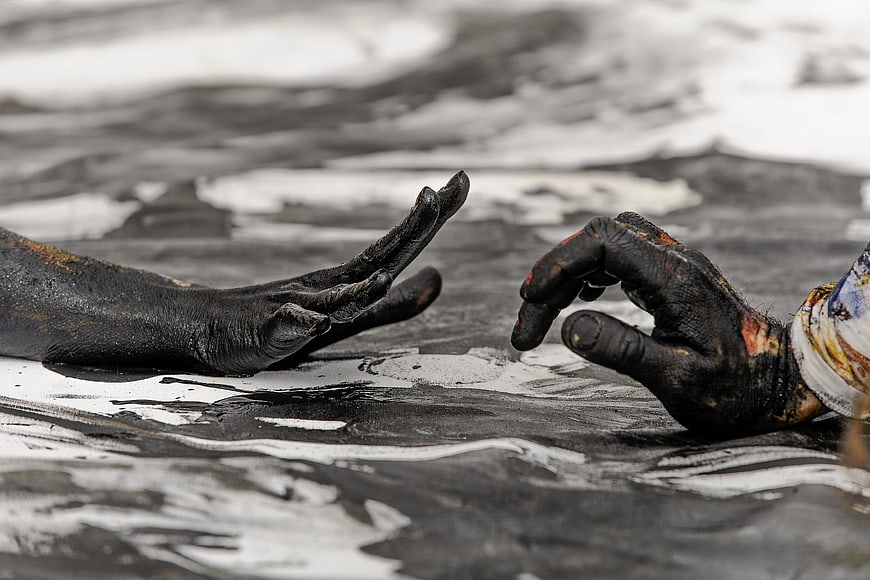 Two hands covered in black paint reaching toward each other