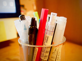 Close-up of colorful pens and markers in a clear cup
