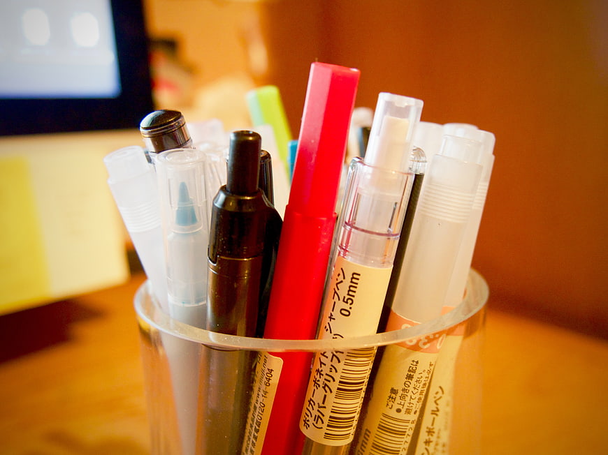 Close-up of colorful pens and markers in a clear cup